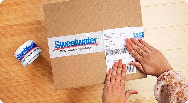 Foto: una persona prepara una scatola per la spedizione.  Il nastro da imballaggio sulla scatola è etichettato con il logo Sweetwater.