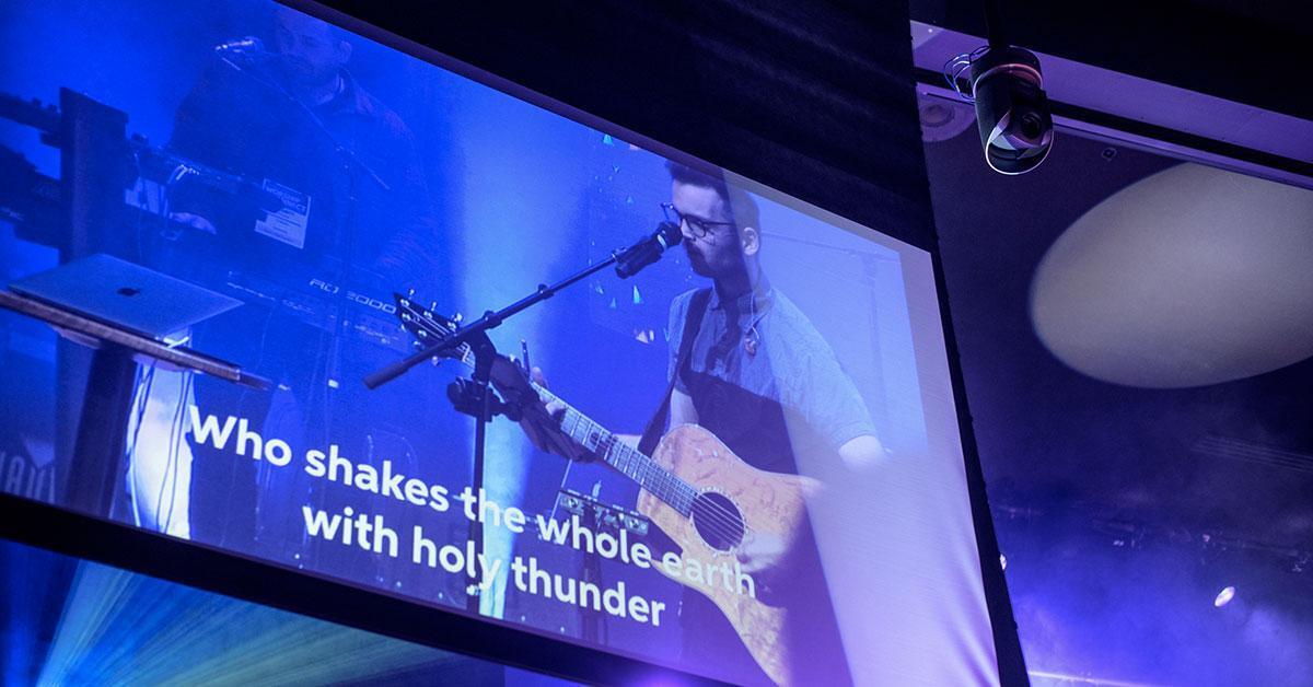 picture of man leading worship on big screen at church