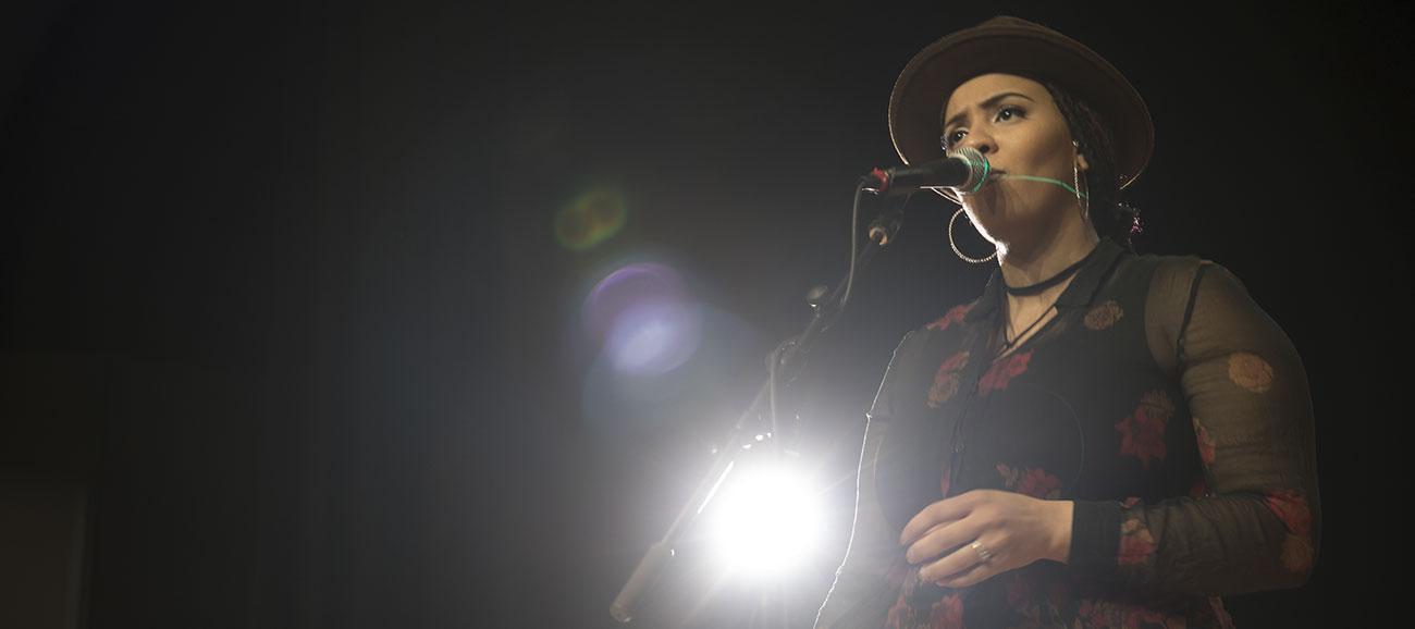 female vocalist singing into a handheld dynamic microphone